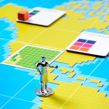 Load image into Gallery viewer, Toy robot figure on a colorful grid map with color swatches in the background