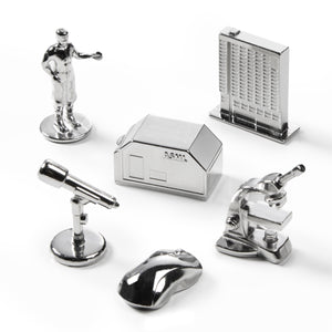 Collection of silver office supplies including a house-shaped phone, mouse, and other items on a white background.